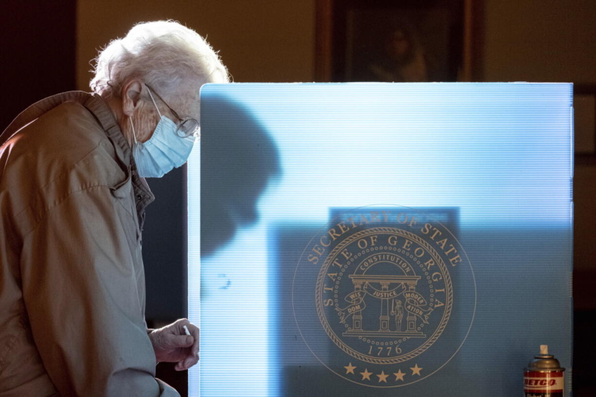 FILE - In this Jan. 5, 2021 file photo, Helen Thomason marks her ballot at the Lawrenceville Road United Methodist Church in Tucker, Ga. during the Senate runoff election. Voting integrity activists argue several parts of Georgia's new election law criminalize normal election observation activities. The state argues that those provisions reinforce previous protections and are necessary for election security. A federal judge is set to hear arguments Thursday, July 1 on the activists' request that he bar election officials from enforcing those provisions.