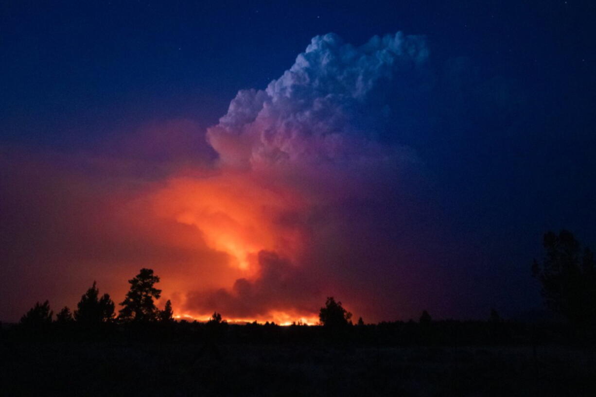 In this photo provided by the Oregon Office of State Fire Marshall, flames and smoke rise from the Bootleg fire in southern Oregon on Wednesday, July 14, 2021. The largest fire in the U.S. on Wednesday was burning in southern Oregon, to the northeast of the wildfire that ravaged a tribal community less than a year ago. The lightning-caused Bootleg fire was encroaching on the traditional territory of the Klamath Tribes, which still have treaty rights to hunt and fish on the land, and sending huge, churning plumes of smoke into the sky visible for miles.