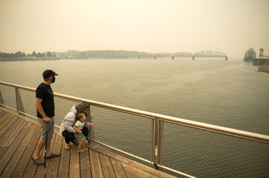 Brent McCarthy, left, and Marissa Matthews, right, play on the Vancouver Waterfront pier with their son Xavier, 2, on Sept. 10, 2020. The family evacuated from their home just outside of Salem, Ore., two days earlier to escape the smoke and fire risk. Longer and hotter fire seasons increase the likelihood of smoke finding its way to Vancouver.