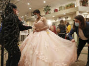 Nataly Contreras, 14, tries on a quinceanera dress as her sister-in-law, Cristal Contreras, right, and Peaches Boutique owner Barb Surdej, left, help at the boutique, 5915 S. Archer Ave., Saturday, Feb. 27, 2021, in Chicago. (John J.