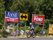 A cyclist passes signs for the upcoming election along Northwest Lakeshore Avenue on the afternoon of July 22.