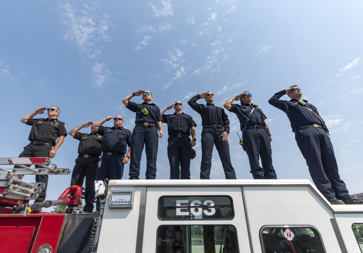 EMT's and firefighters from Clark County Fire District 6 stand atop a firetruck and salute as a funeral procession for Clark County Sheriff's Sgt. Jeremy Brown drives north on I-5 on Tuesday, Aug. 3, 2021, at the NE 139th Street overpass in Vancouver.