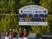 Ridgefield Raptors players gather in the infield as pitcher Carson Walters warms up at the mound in the fith inning against the Cowlitz Black Bears at Ridgefield Outdoor Recreation Complex on Wednesday, August 4, 2021.