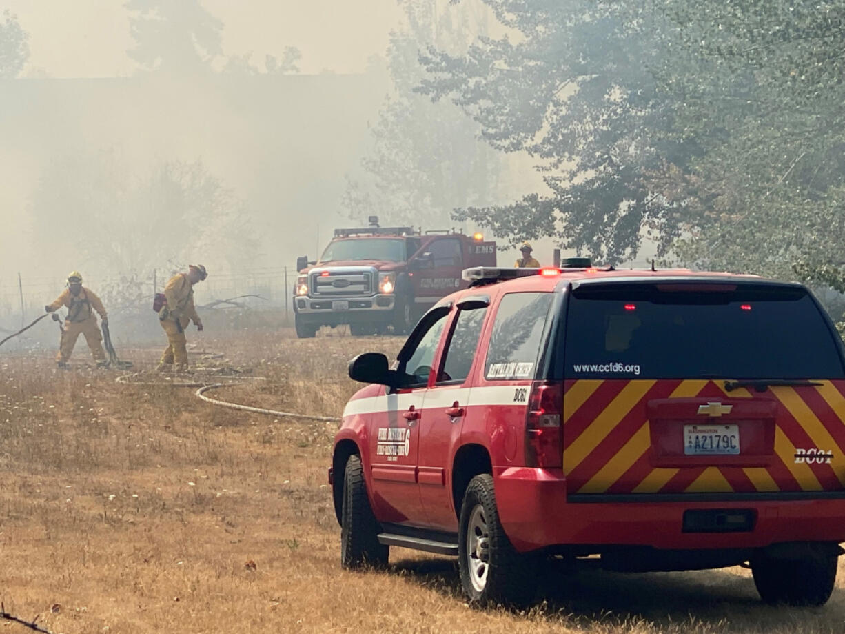 Clark County Fire District 6 crews battle a stubborn brush fire Monday afternoon near Klineline Pond. Pushed by shifting winds and fueled by dry underbrush, the brush fire sent smoke billowing toward Interstate 5.