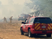 Clark County Fire District 6 crews battle a stubborn brush fire Monday afternoon near Klineline Pond. Pushed by shifting winds and fueled by dry underbrush, the brush fire sent smoke billowing toward Interstate 5.