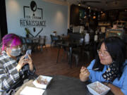 Jennifer Le of Vancouver, left, enjoys a treat at Ice Cream Renaissance in Uptown Village with her sister, Julie, on Monday afternoon. Washington's renewed indoor mask mandate took effect Monday.