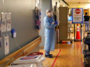 Registered nurse Diane Miller stands in the "hot zone," defined by red tape on the floor, as she waits to exchange equipment with a colleague who will remain on the other side of the tape in the COVID acute care unit at UW Medical Center-Montlake, Tuesday, Jan. 26, 2021, in Seattle. King County, where the hospital is located, has been on a downward trend of COVID-19 cases after two-and-a-half straight months of increases. But the current lull could be, and some experts believe will be, upended as more contagious variants of the virus spread throughout United States.