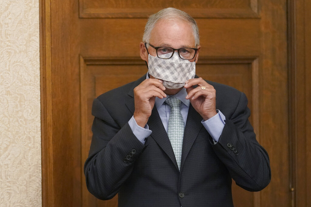 Washington Gov. Jay Inslee puts on a mask after speaking at a news conference, Wednesday, Aug. 18, 2021, at the Capitol in Olympia, Wash. Inslee announced that Washington state is expanding its vaccine mandate to include all public, charter and private school teachers and staff, as well as those working at the state's colleges and universities. The governor also expanded the statewide indoor mask mandate in place for non-vaccinated individuals to include those who are vaccinated. (AP Photo/Ted S.