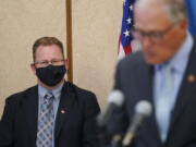 Washington state Superintendent of Public Instruction Chris Reykdal, left, listens as Gov. Jay Inslee speaks at a news conference, Wednesday, Aug. 18, 2021, at the Capitol in Olympia, Wash. Inslee announced that Washington state is expanding its vaccine mandate to include all public, charter and private school teachers and staff, as well as those working at the state's colleges and universities. Inslee also expanded the statewide indoor mask mandate in place for non-vaccinated individuals to include those who are vaccinated. (AP Photo/Ted S.