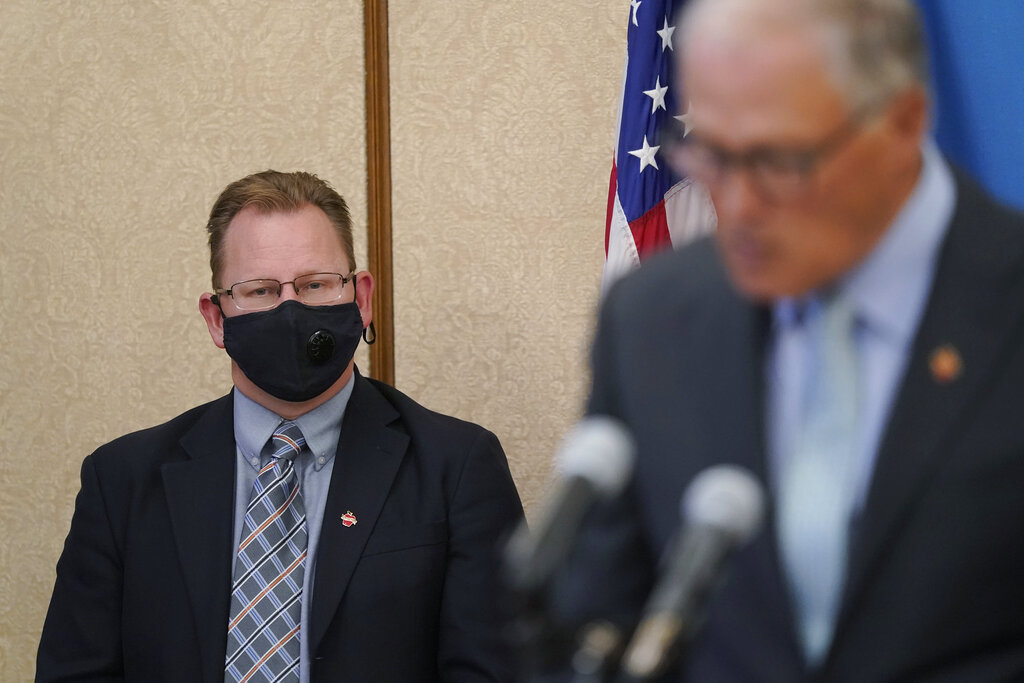 Washington state Superintendent of Public Instruction Chris Reykdal, left, listens as Gov. Jay Inslee speaks at a news conference, Wednesday, Aug. 18, 2021, at the Capitol in Olympia, Wash. Inslee announced that Washington state is expanding its vaccine mandate to include all public, charter and private school teachers and staff, as well as those working at the state's colleges and universities. Inslee also expanded the statewide indoor mask mandate in place for non-vaccinated individuals to include those who are vaccinated. (AP Photo/Ted S.