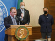 Washington State Superintendent of Public Instruction Chris Reykdal, left, holds up a face mask as he speaks at a news conference, along with Gov. Jay Inslee, center, and Secretary of Health Umair A. Shah, right, at the Capitol, Wednesday, Aug. 18, 2021, in Olympia, Wash. Inslee announced that Washington state is expanding its vaccine mandate to include all public, charter and private school teachers and staff, as well as those working at the state's colleges and universities. The Governor also expanded the statewide indoor mask mandate in place for non-vaccinated individuals to include those who are vaccinated. (AP Photo/Ted S.