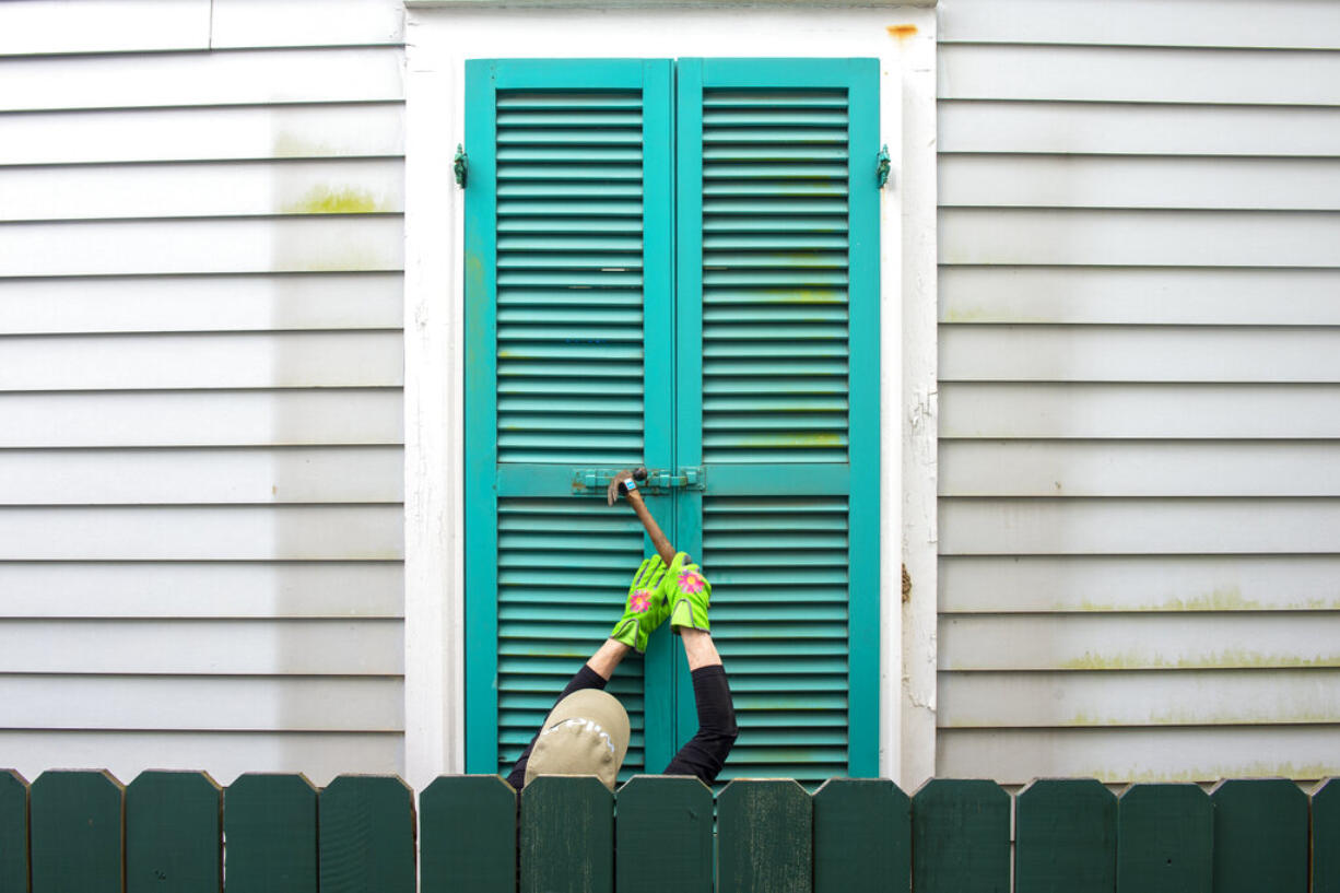 Storm shutters are hammered closed on a 100-year-old house, Friday, August 27, 2021, in New Orleans, as residents prepare for Hurricane Ida.