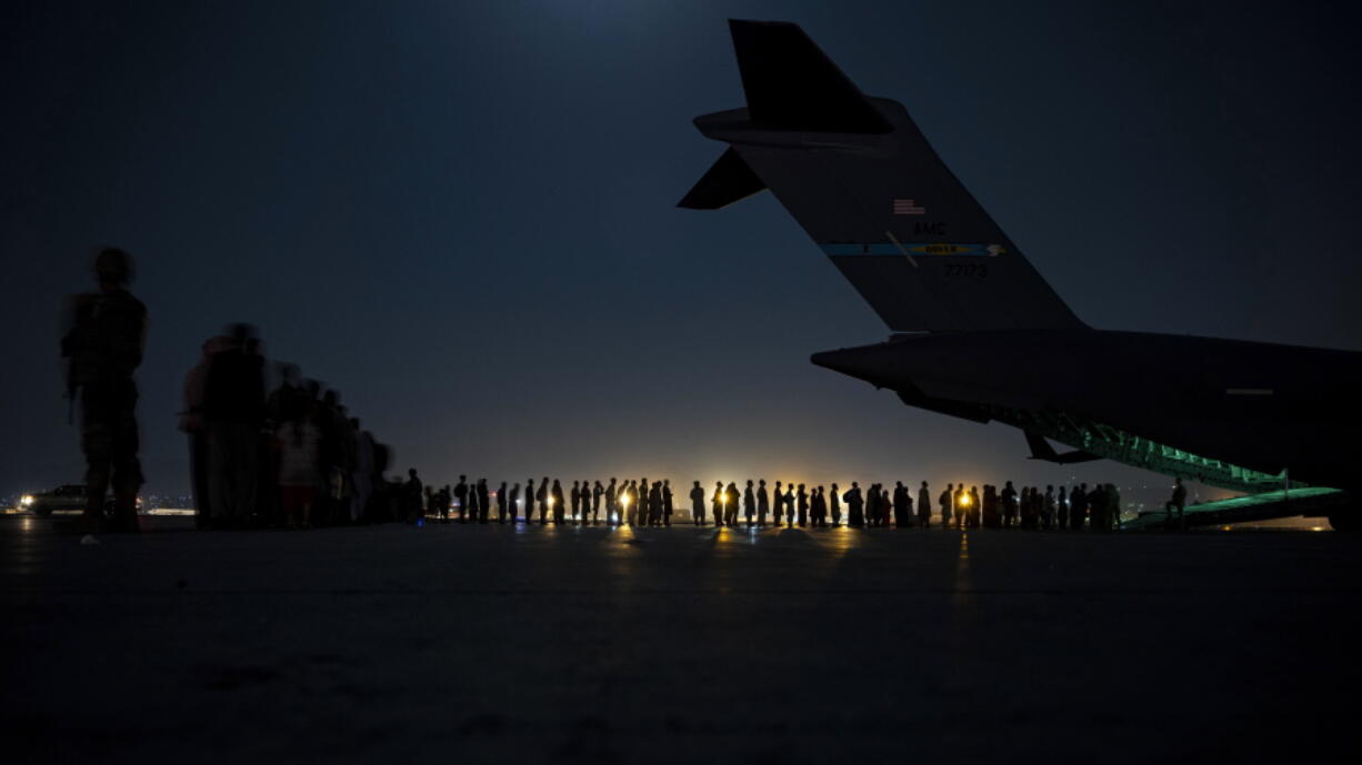 In this image provided by the U.S. Air Force, U.S. Air Force aircrew, assigned to the 816th Expeditionary Airlift Squadron, prepare to load qualified evacuees aboard a U.S. Air Force C-17 Globemaster III aircraft in support of the Afghanistan evacuation at Hamid Karzai International Airport, Kabul, Afghanistan, Saturday, Aug. 21, 2021. (Senior Airman Taylor Crul/U.S.