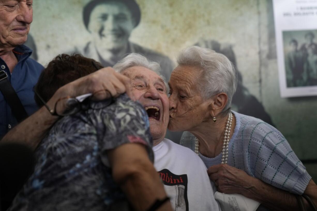 Martin Adler, center, a 97-year-old Army veteran, receives a kiss from Mafalda, right, and Giuliana Naldi, whom he saved during WWII, at Bologna, Italy's airport on Monday.