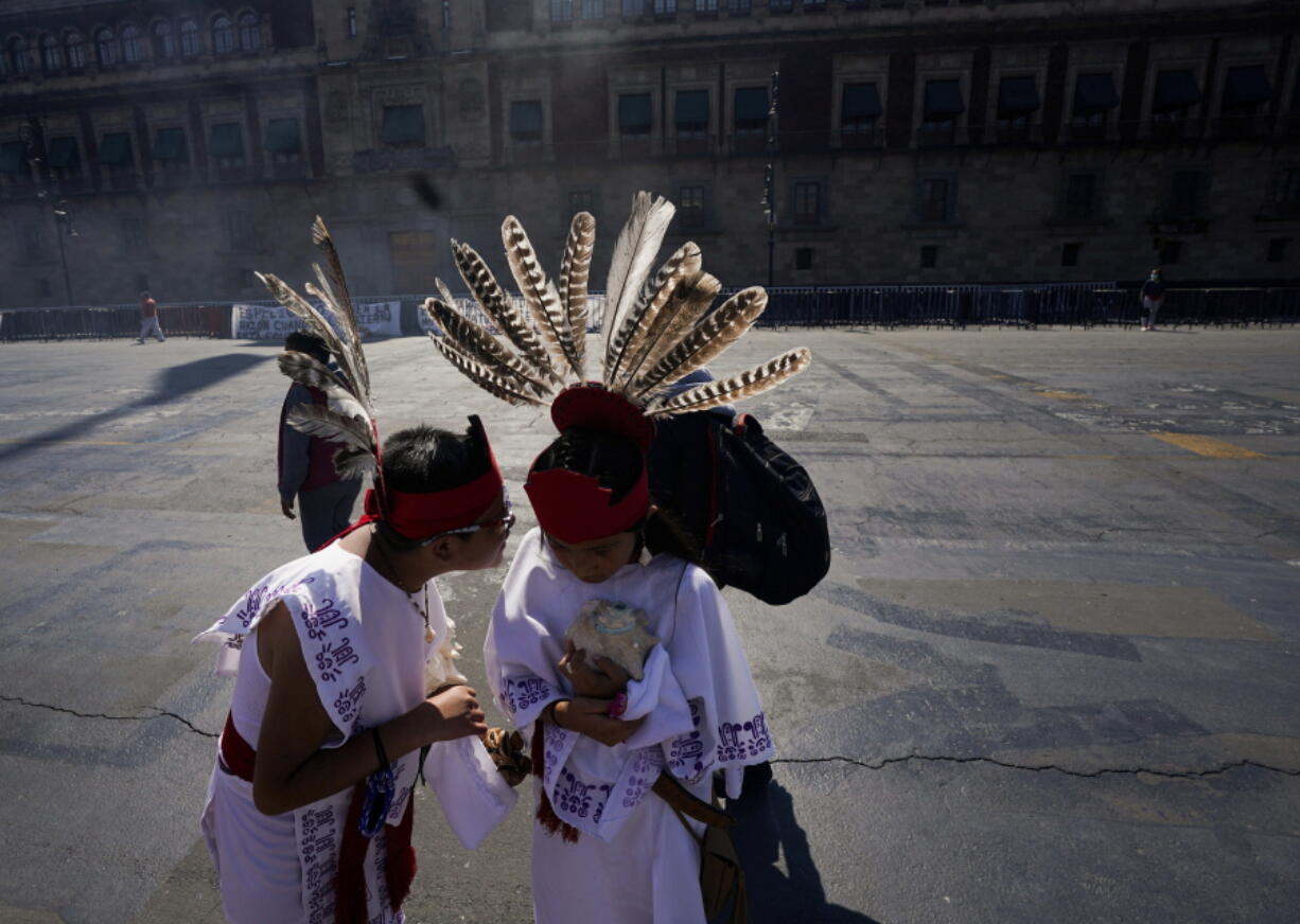 Two young dancers speak Monday before a performance as part of the commemoration marking the 700 year anniversary of the founding of the Aztec city of Tenochtitlan, known today as Mexico City, at Zocalo square in Mexico City.