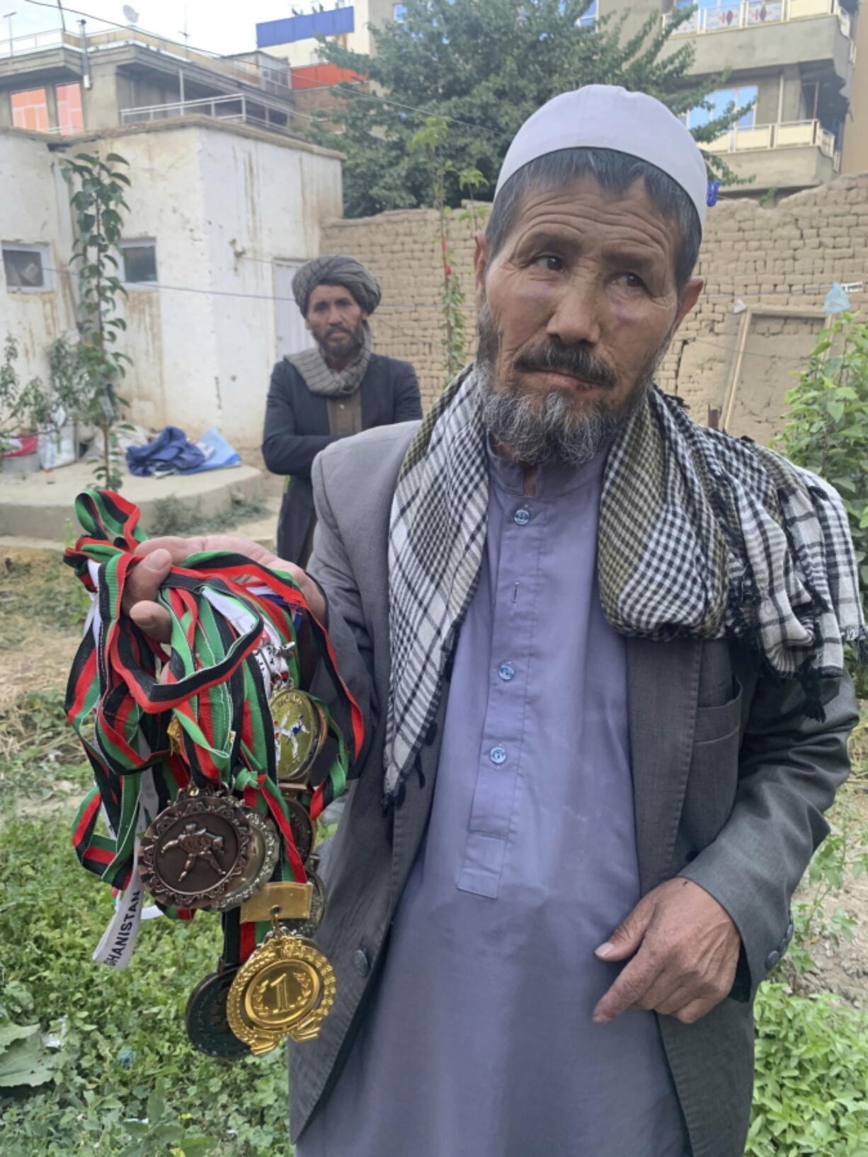 Mohammed Jan Sultani's father, Ali, holds his son's awards during an interview with The Associated Press in Kabul, Afghanistan, Sunday, Aug. 29, 2021. Mohammed Jan Sultani had clutched his national Taekwondo championship certificates as he waded through the multitudes pushing to get into Kabul airport late last week.