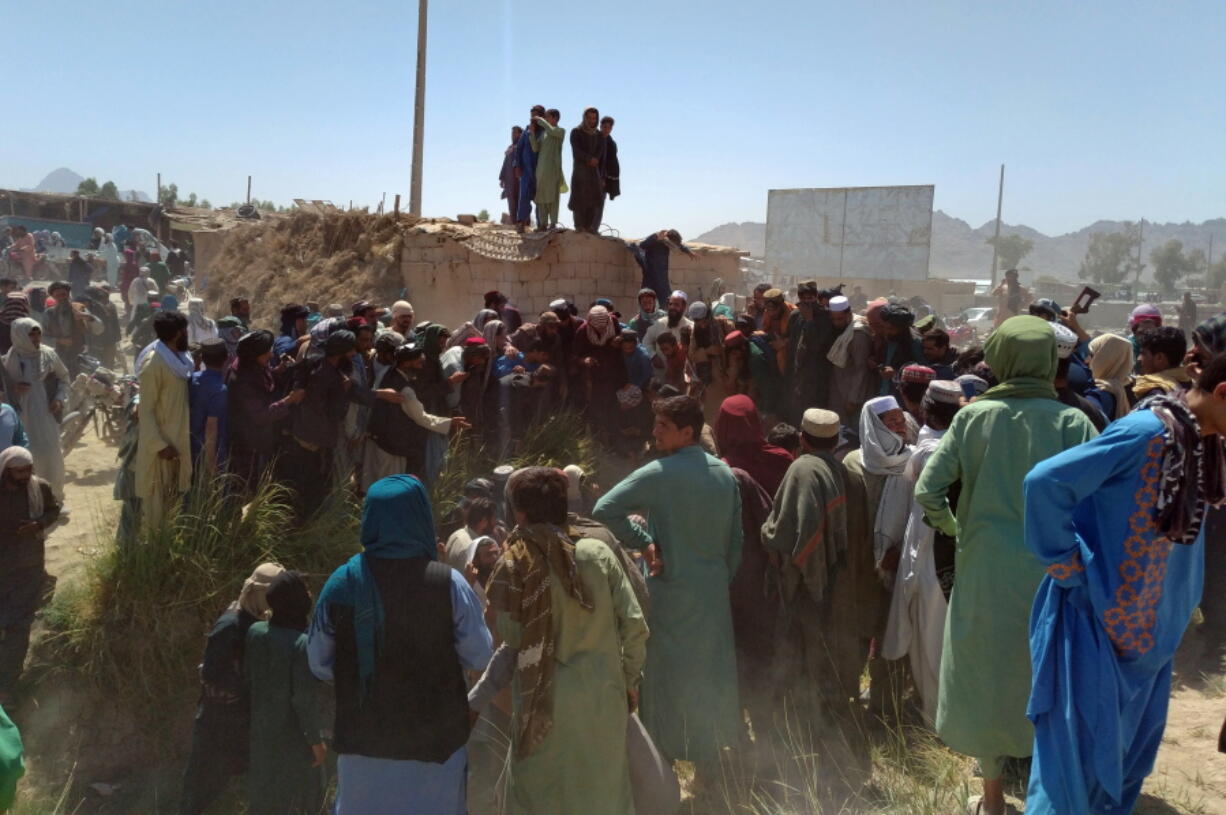 Taliban fighters and Afghans gather around the body of a member of the security forces who was killed, inside the city of Farah, capital of Farah province, southwest Afghanistan, Wednesday, Aug. 11, 2021. Afghan officials say three more provincial capitals have fallen to the Taliban, putting nine out of the country's 34 in the insurgents' hands amid the U.S. withdrawal. The officials told The Associated Press on Wednesday that the capitals of Badakhshan, Baghlan and Farah provinces all fell.