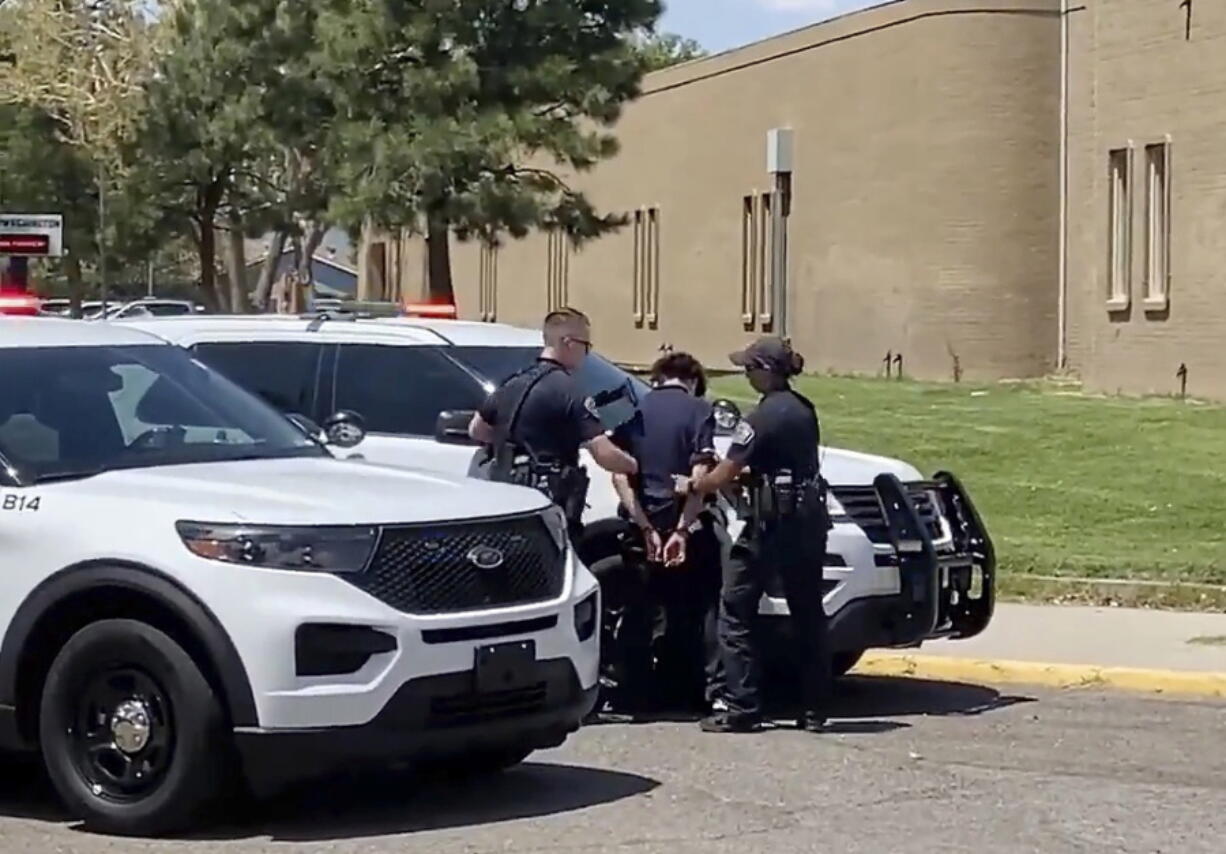 In this image from taken from video courtesy of Ryan Laughlin/KOB 4 TV Albuquerque Police Department officers search a student after a shooting at Washington Middle School which left at least one student dead and another in custody, police said Friday, Aug. 13, 2021. Only a few days into the new school year and New Mexico's largest district was left reeling from the shooting. Authorities said Friday's shooting was an isolated incident between two Washington Middle School students who were believed to be about 13 years old.