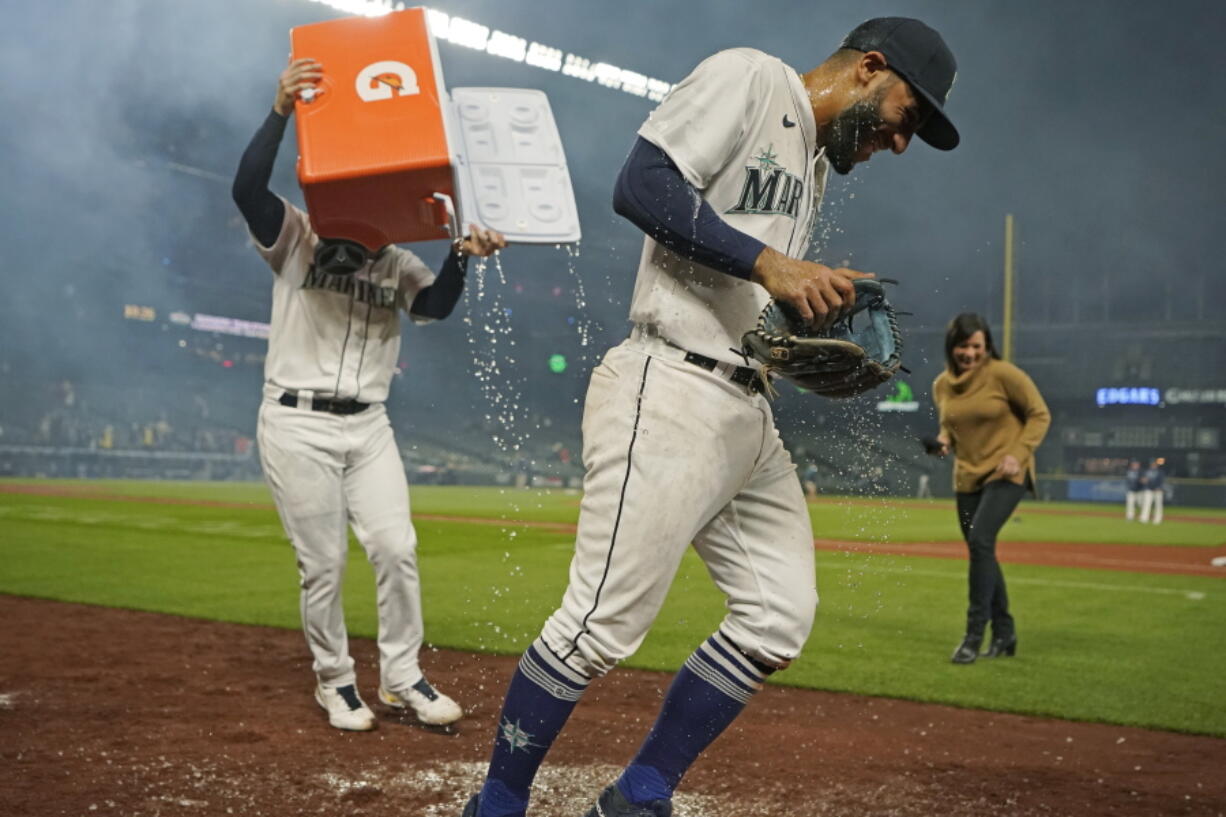 Seattle Mariners' Abraham Toro, center, has a cooler of water dumped on him by teammate Luis Torrens, left, as Toro takes part in an interview after the team's baseball game against the Houston Astros, Tuesday, Aug. 31, 2021, in Seattle. Toro hit a grand slam in the eighth inning to give the Mariners a 4-0 win. (AP Photo/Ted S.