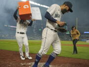 Seattle Mariners' Abraham Toro, center, has a cooler of water dumped on him by teammate Luis Torrens, left, as Toro takes part in an interview after the team's baseball game against the Houston Astros, Tuesday, Aug. 31, 2021, in Seattle. Toro hit a grand slam in the eighth inning to give the Mariners a 4-0 win. (AP Photo/Ted S.