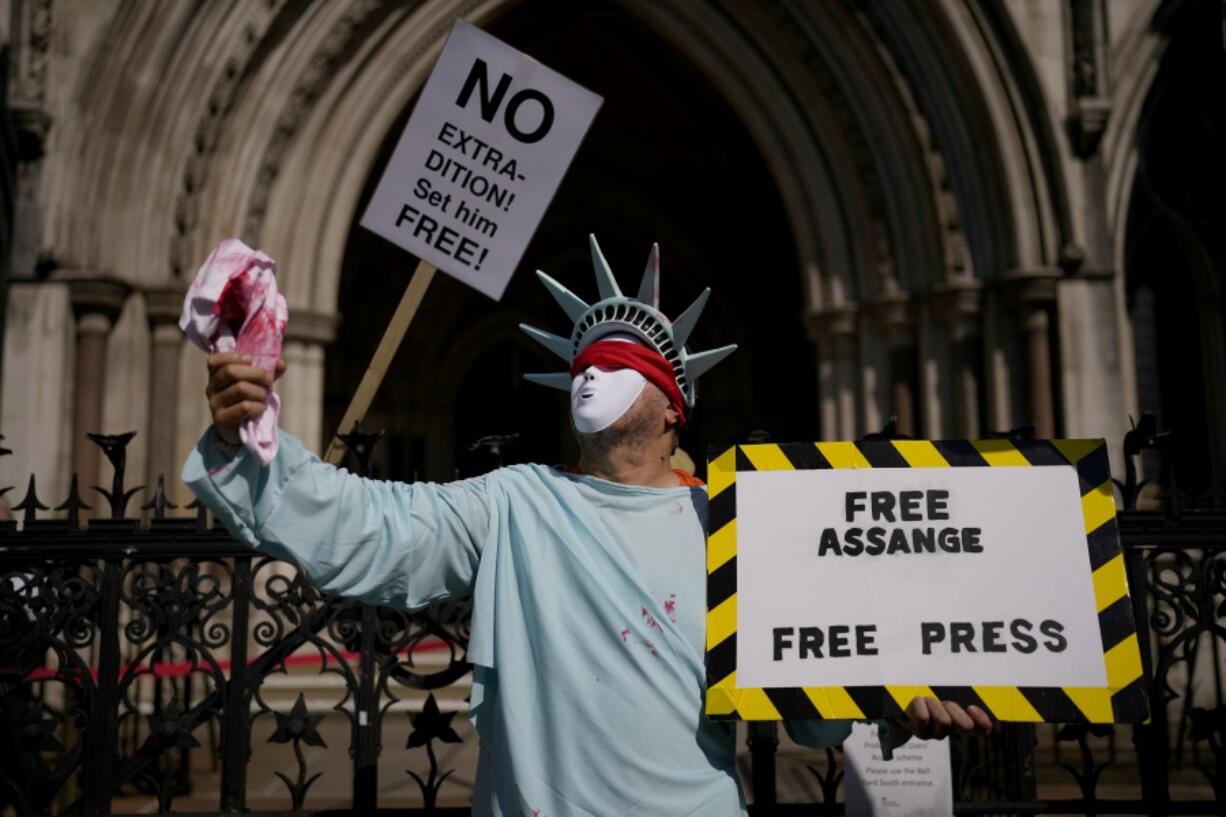 A supporter of WikiLeaks founder Julian Assange demonstrates dressed as the Statue of Liberty, during the first hearing in the Julian Assange extradition appeal, at the High Court in London, Wednesday, Aug. 11, 2021. Britain's High Court has granted the U.S. government permission to appeal a decision that WikiLeaks founder Julian Assange cannot be sent to the United States to face espionage charges.