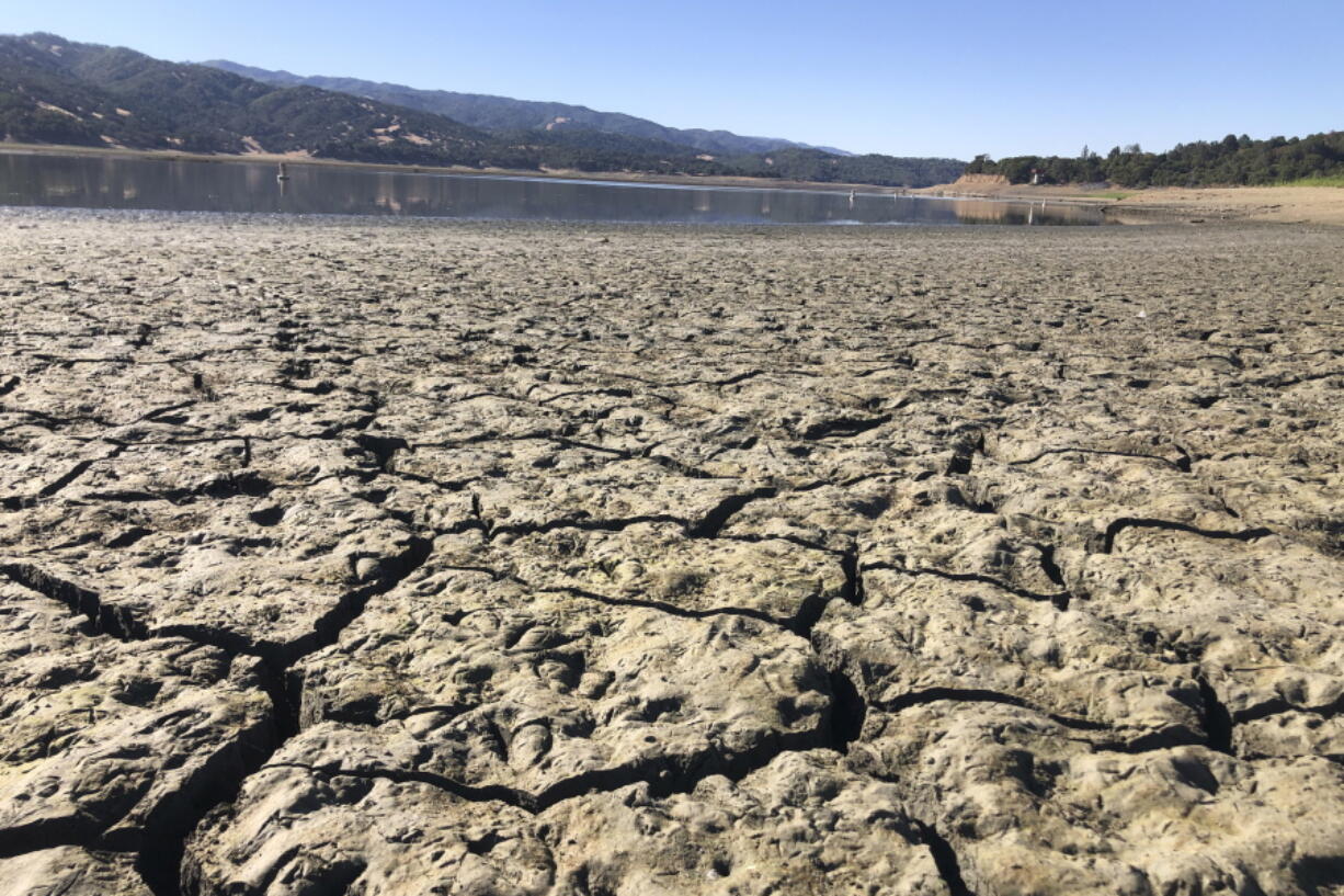 An exposed dry bed is seen at Lake Mendocino near Ukiah, Calif., Wednesday, Aug. 4, 2021. Tourists flock to the picturesque coastal town of Mendocino for its Victorian homes and cliff trails, but visitors this summer will also find public portable toilets and dozens of signs on picket fences announcing the quaint Northern California hamlet: "Severe Drought Please conserve water." The town of Mendocino gets some of their water from the reservoir, but most of the lake water goes to Sonoma County.