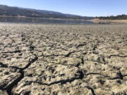 An exposed dry bed is seen at Lake Mendocino near Ukiah, Calif., Wednesday, Aug. 4, 2021. Tourists flock to the picturesque coastal town of Mendocino for its Victorian homes and cliff trails, but visitors this summer will also find public portable toilets and dozens of signs on picket fences announcing the quaint Northern California hamlet: "Severe Drought Please conserve water." The town of Mendocino gets some of their water from the reservoir, but most of the lake water goes to Sonoma County.