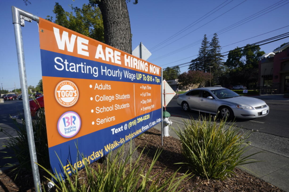 A car passes a hiring banner in Sacramento, Calif., Friday, July 16, 2021. Hiring in California slowed down in June 2021 as employers in the nation's most populous state tried to coax reluctant workers back into their pre pandemic jobs before the nation's expanded unemployment benefits expire in September.