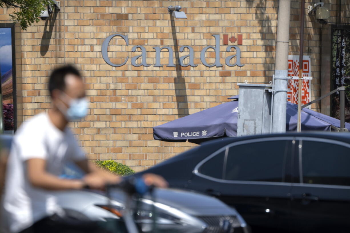 A man rides a scooter across an intersection near the Canadian Embassy in Beijing, Tuesday, Aug. 10, 2021. A Chinese court has rejected an appeal by a Canadian whose sentence in a drug case was increased to death after an executive of tech giant Huawei was detained in Vancouver.