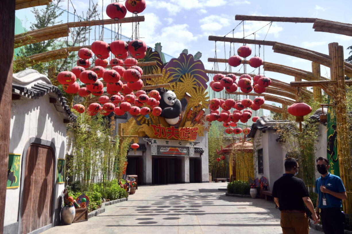 FILE - In this Wednesday, May 26, 2021 file photo, men wearing masks stand inside the Universal Studios theme park, part of the Universal Beijing Resort, under construction in Beijing, China. Universal Studios announced Monday, Aug 30, 2021 that its first theme park in China will open in the country's capital in September. The company set the opening date for Sept. 20, according to a statement and video posted on the Chinese social media site WeChat.