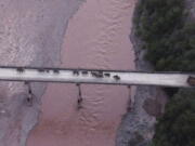 In this photo released by the Yunnan Provincial Command Center for the Safety and Monitoring of North Migrating Asian Elephants, a herd of wandering elephants cross a river using a highway near Yuxi city, Yuanjiang county in southwestern China's Yunnan Province Sunday, Aug. 8, 2021. The 14 elephants of various sizes and ages were guided across the Yuanjiang river in Yunnan province on Sunday night and a path is being opened for them to return to the nature reserve in the Xishuangbanna Dai Autonomous Prefecture.