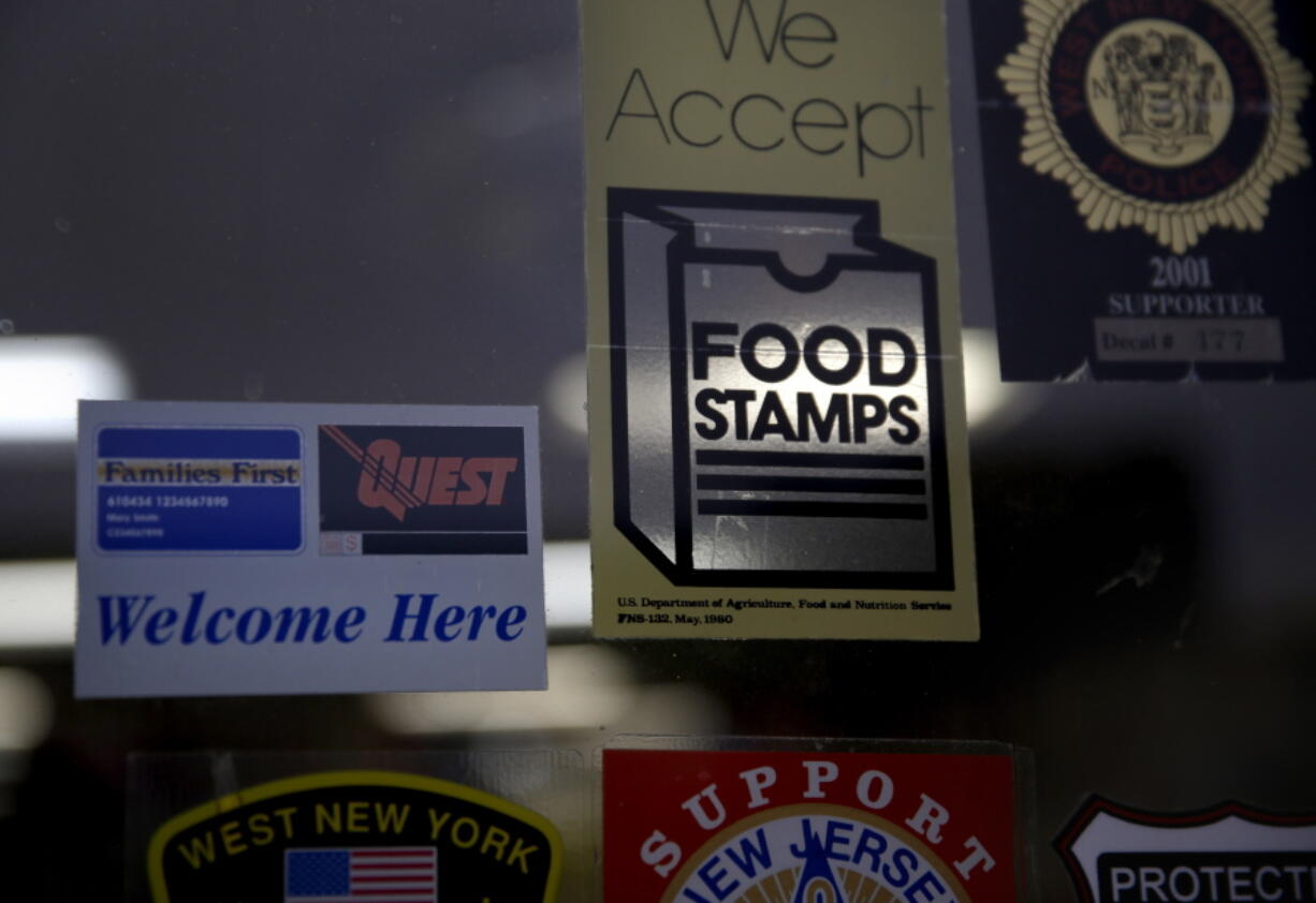 FILE - In this Jan. 12, 2015 file photo, a supermarket displays stickers indicating they accept food stamps in West New York, N.J. The Biden administration has approved a significant and permanent increase in the levels of food stamp assistance available to needy families--the largest single increase in the program's history. Starting in October 2021, average benefits for food stamps (officially known as the SNAP program) will rise more than 25 percent above pre-pandemic levels.