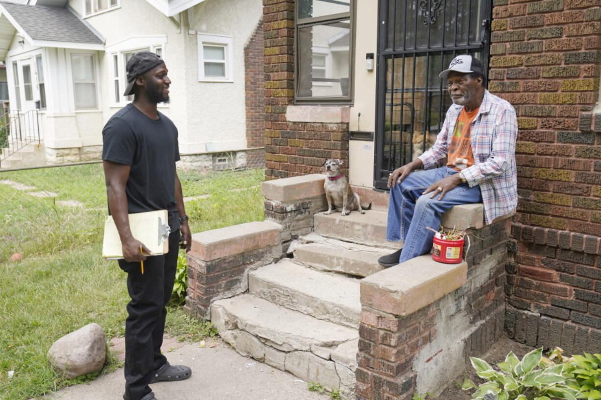 Organizer Latrell Snider, left, talks with Minneapolis resident Steven Black on July 22, 2021, ahead of the November election, as small armies of door-knockers are hitting the Minneapolis streets seeking to build support for a ballot question that would eliminate the city's police department and replace it with something new. It's the second such attempt by activists and some elected officials since George Floyd died at the hands of city police after last year's effort didn't make the ballot.