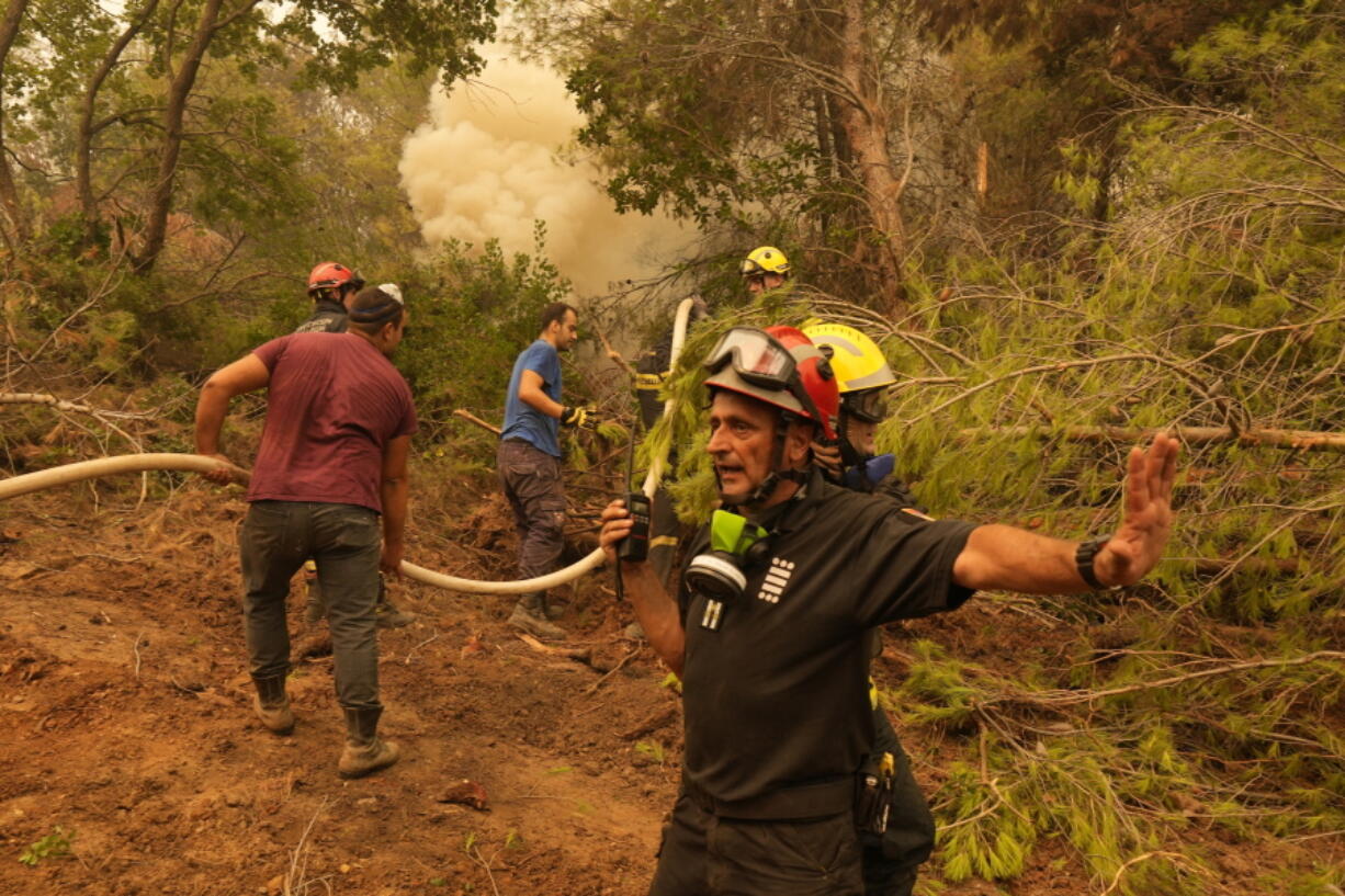 A firefighter from Serbia directs his colleagues during a wildfire at Kamaria village on Evia island, about 189 kilometers (114 miles) north of Athens, Greece, Tuesday, Aug. 10, 2021.