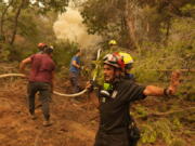 A firefighter from Serbia directs his colleagues during a wildfire at Kamaria village on Evia island, about 189 kilometers (114 miles) north of Athens, Greece, Tuesday, Aug. 10, 2021.