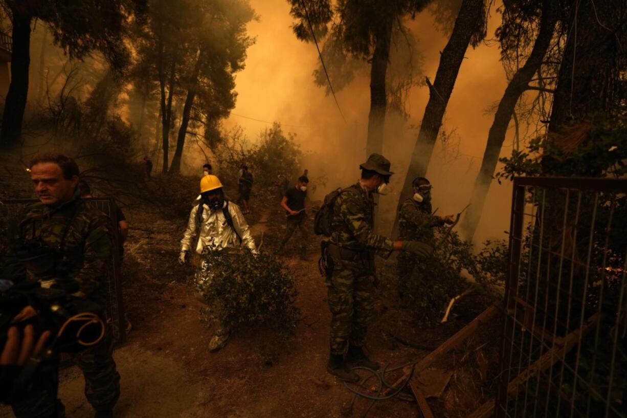 People try to extinguish the flames during a wildfire at Pefki village on Evia island, about 189 kilometers (118 miles) north of Athens, Greece, Sunday, Aug. 8, 2021. Pillars of billowing smoke and ash are blocking out the sun above Greece's second-largest island as a days-old wildfire devours pristine forests and triggers more evacuation alerts.