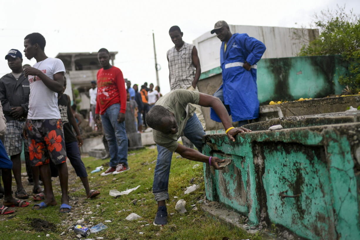 A cemetery worker opens a used tomb to place the body of a boy who was found in a collapsed building in Les Cayes, Haiti, Tuesday, Aug. 17, 2021, three days after a 7.2 magnitude earthquake hit. According to an engineer working for Les Cayes Mayor, the boy's body was found Monday amid the rubble of a collapsed hostal.