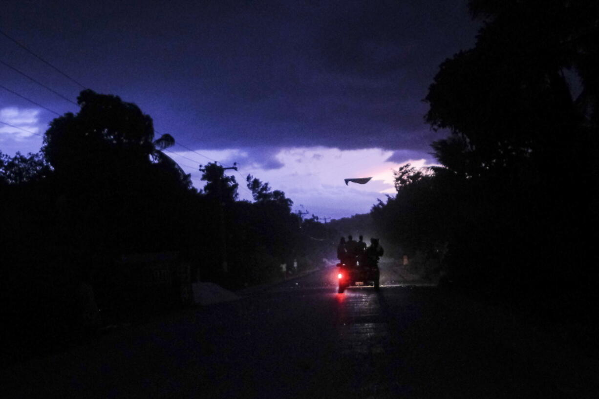 Commuters travel on a bus popularly referred to as "tap-tap" during a tropical storm in Miragoane, Haiti, Sunday, Aug. 15, 2021.