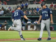 Seattle Mariners' Ty France (23) is congratulated by third base coach Manny Acta (14) after hitting a two-run home run off Texas Rangers relief pitcher Joe Barlow during the 11th inning of a baseball game Thursday, Aug. 19, 2021, in Arlington, Texas. Seattle won 9-8.