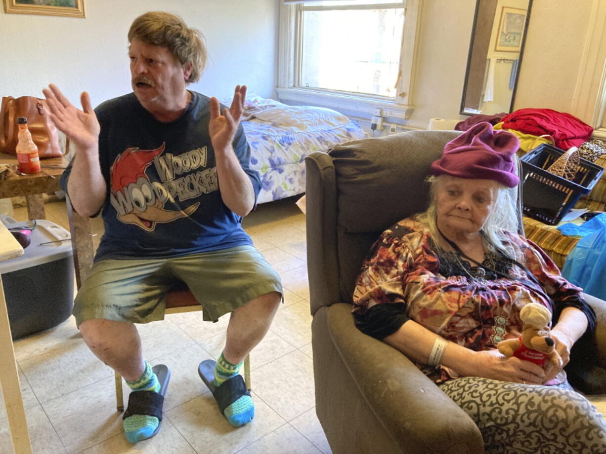 Karen Colby listens on July 22, 2021 in Portland, Ore., while her neighbor Joel Aslin tells how he called an ambulance for her when she got heat stroke as temperatures reached 107 F in her small fifth-floor studio apartment during a record-breaking heat wave in June. The unprecedented heat, which reached 116 F in Portland, killed dozens of people in Oregon and hundreds across the region and was a wake-up call for the normally cool region as climate change accelerates.