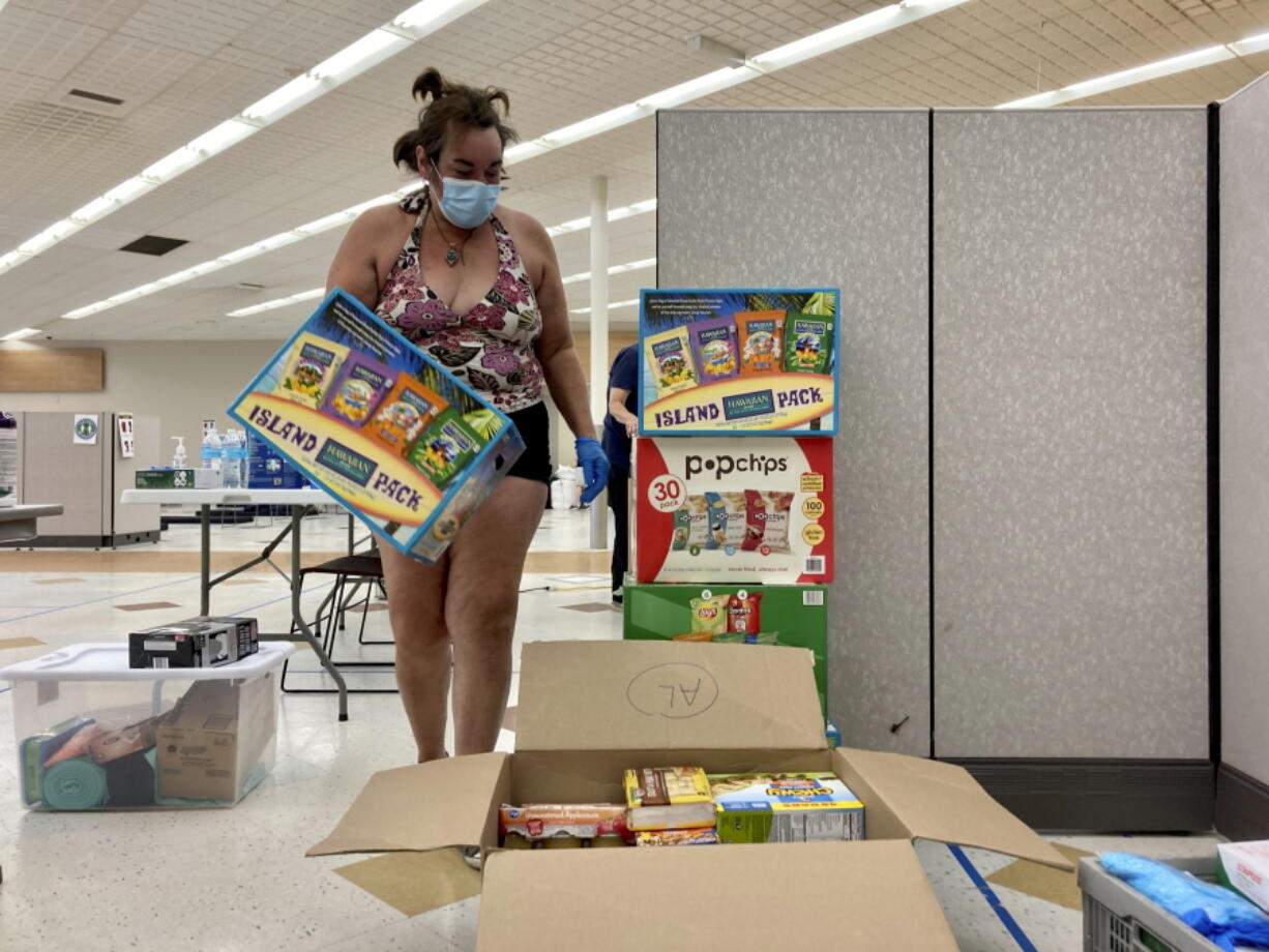 December Snedecor, a homeless woman who lives in a tent in Portland, Ore., helps set up snacks at a cooling center established to help vulnerable residents ride out the second dangerous heat wave to grip the Pacific Northwest this summer on Wednesday, Aug. 11, 2021. Snedecor, 46, spent two nights at the same cooling center in June when temperatures in the city soared to 116 degrees Fahrenheit and she plans to spend the night there again this week as temperatures are forecast to hit 100 F or higher for three consecutive days.