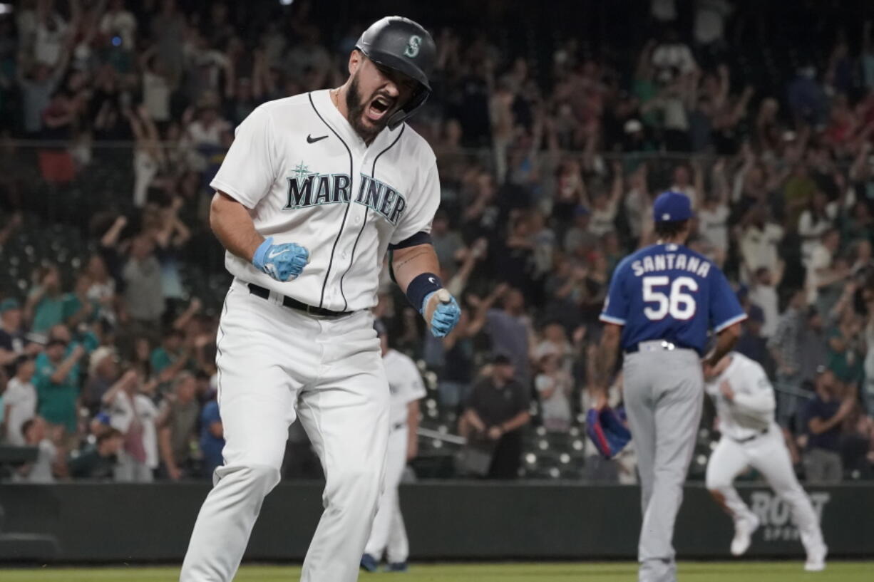 Seattle Mariners' Luis Torrens, left, celebrates his single that scored Jarred Kelenic with the winning run off of Texas Rangers pitcher Dennis Santana (56) during the ninth inning of a baseball game Wednesday, Aug. 11, 2021, in Seattle. The Mariners won 2-1. (AP Photo/Ted S.