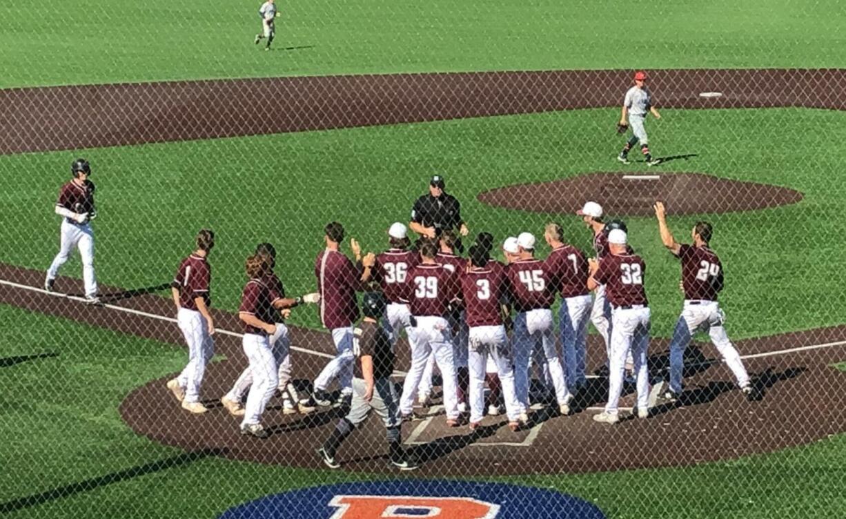 The Ridgefield Raptors await John Peck at home plate after his game-winning home run in the 11th inning against the Walla Walla Sweets on Sunday at Ridgefield Outdoor Recreation Complex.