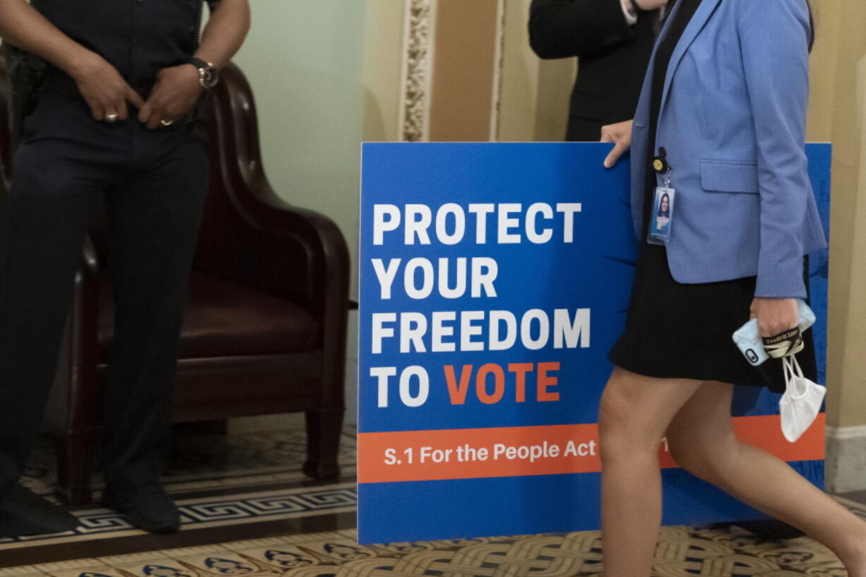 FILE - In this June 22, 2021, file photo, an aide carries a sign to the Senate floor before test vote on the For the People Act, a sweeping bill that would overhaul the election system and voting rights, at the Capitol in Washington. Both parties are bracing for a major legal fight over redistricting. Democrats need court wins more than Republicans because they control the redrawing of political maps in far fewer states than the GOP.