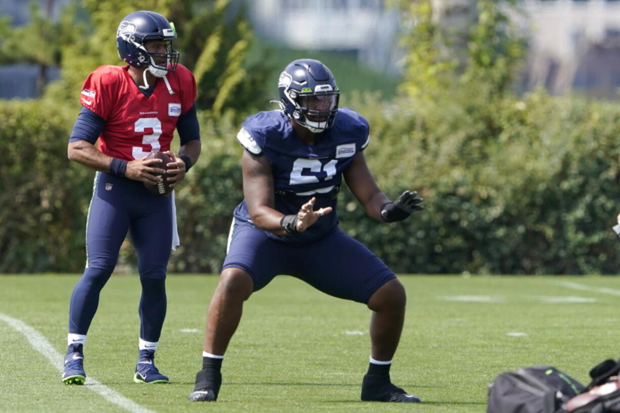 Seattle Seahawks quarterback Russell Wilson (3) takes a snap from center Kyle Fuller during NFL football practice Wednesday, Aug. 25, 2021, in Renton, Wash. (AP Photo/Ted S.