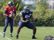 Seattle Seahawks quarterback Russell Wilson (3) takes a snap from center Kyle Fuller during NFL football practice Wednesday, Aug. 25, 2021, in Renton, Wash. (AP Photo/Ted S.