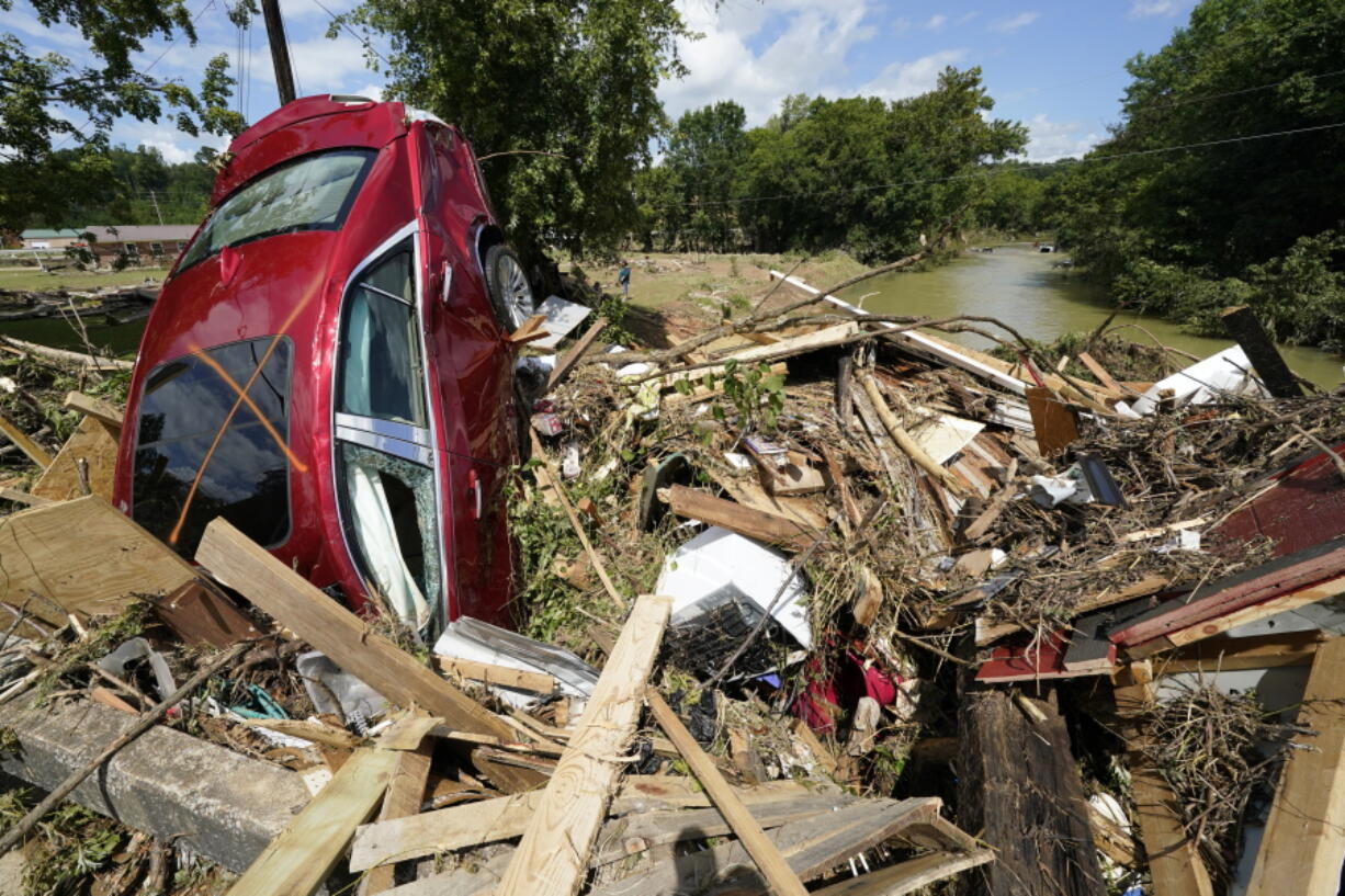 A car is among debris that washed up against a bridge over a stream Sunday, Aug. 22, 2021, in Waverly, Tenn. Heavy rains caused flooding Saturday in Middle Tennessee and have resulted in multiple deaths as homes and rural roads were washed away.