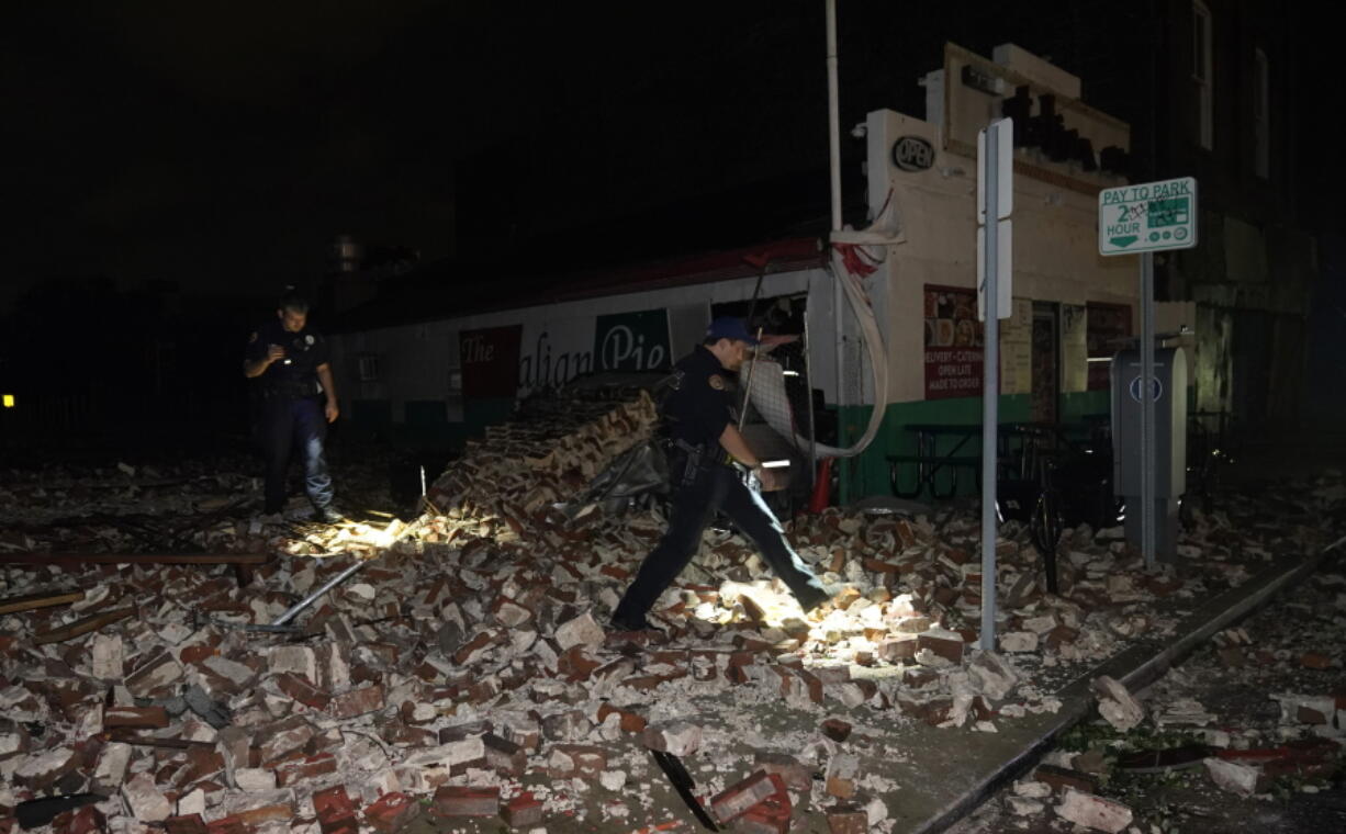 Police look through debris after a building collapsed from the effects of Hurricane Ida, Monday, Aug. 30, 2021, in New Orleans, La. Hurricane Ida knocked out power to all of New Orleans and inundated coastal Louisiana communities on a deadly path through the Gulf Coast that is still unfolding and promises more destruction.