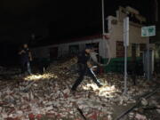 Police look through debris after a building collapsed from the effects of Hurricane Ida, Monday, Aug. 30, 2021, in New Orleans, La. Hurricane Ida knocked out power to all of New Orleans and inundated coastal Louisiana communities on a deadly path through the Gulf Coast that is still unfolding and promises more destruction.