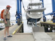 Robin Berthet, of Sheffield, Mass., watches as his sailboat is hauled out of the water onto dry land in advance of an expected storm, Friday Aug. 20, 2021, in Plymouth, Mass. New Englanders, bracing for their first direct hit by a hurricane in 30 years, are taking precautions as Tropical Storm Henri barrels toward the southern New England coast.